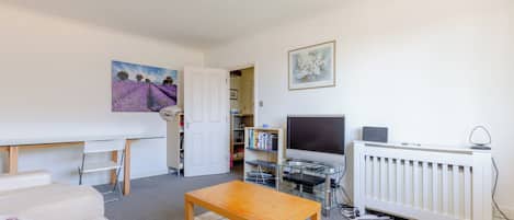 A living room with a sofa, a wooden coffee table, a TV, and a radiator.