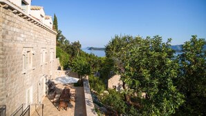A stone building with a patio, outdoor seating, and a view of the sea.