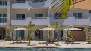 A hotel with a pool, outdoor seating, and a palm tree.