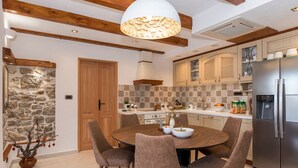 A modern kitchen with a stone wall, wooden beams, and a central island. - Villa Klementina - Three Bedroom Villa, Sleeps 6 (Bicine)