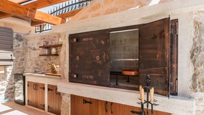 Une cuisine rustique avec des murs en pierre, des armoires en bois et une grande porte ouverte.