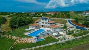 Une grande villa dotée d’une piscine, de plusieurs terrasses et offrant une vue sur le paysage environnant.