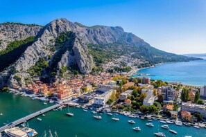 A coastal town with a marina, buildings, and a mountainous backdrop.