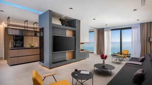 Una sala de estar moderna con un televisor de pantalla plana, un sofá y un comedor con cocina.