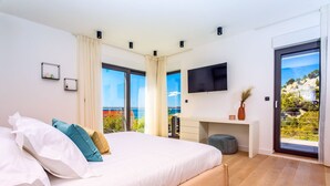 A modern bedroom with a large bed, a desk, and a TV.