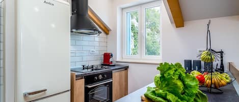 A modern kitchen with a built-in oven, a stove, and a window providing a view of the outdoors.