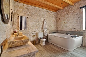 Une salle de bain avec un lavabo en pierre, des toilettes et une grande baignoire.