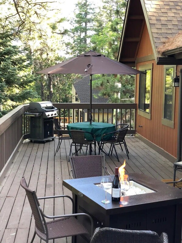 Una terraza con una parrilla, mesa al aire libre, sillas y un hogar para fuego.
