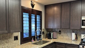 Una cocina moderna con armarios de madera oscura, encimeras de granito, un lavaplatos de acero inoxidable y un microondas integrado.