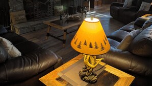 Una sala acogedora con chimenea de piedra, sofás de cuero y una mesa con lámpara.
