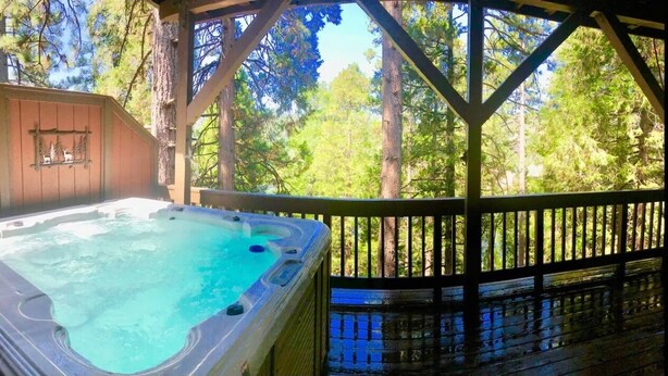 Un jacuzzi en una terraza de madera con vista a un bosque.