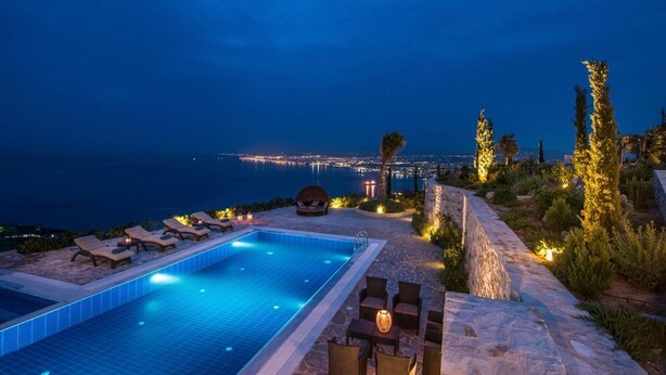 A nighttime pool area with lounge chairs and a view of the cityscape.