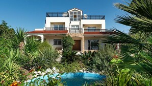 A two-story building with a swimming pool surrounded by tropical plants. - Villa Kalvos - Five Bedroom Villa, Sleeps 10 (Kolympia)