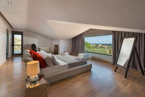 Un dormitorio moderno con una cama grande, una mesita de noche, una lámpara y vistas al campo desde la ventana.