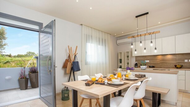 A modern kitchen with a dining area, a large window, and a view of the outdoors.