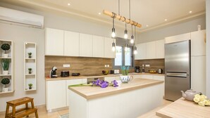 A modern kitchen with white cabinets, a wooden countertop, and a stainless steel refrigerator.