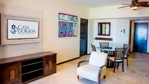 A living room with a TV, artwork, and a dining area with chairs and a table.