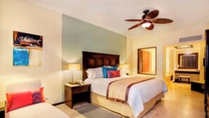 A hotel room with a bed, bedside tables, a ceiling fan, a mirror, and a door leading to a bathroom.
