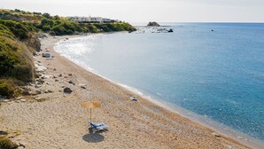 Une plage offrant une vue dégagée sur la mer, quelques rochers épars et un seul parasol.