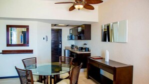 A compact kitchen with dark cabinets, a microwave, and a coffee maker. There is a dining area with a glass table and wooden chairs. - Casa Dorada Los Cabos Resort and Spa (Cabo San Lucas)