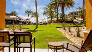 A poolside area with lounge chairs and umbrellas, palm trees, and a building in the background. - Casa Dorada Los Cabos Resort and Spa (Cabo San Lucas)