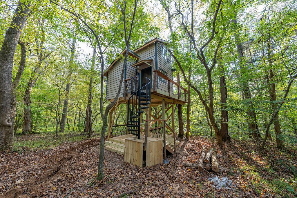 Una casa en un árbol con una escalera de madera y una pequeña plataforma.