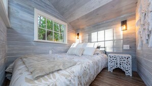 Une chambre à coucher avec un lit, une fenêtre et une table de chevet avec une lampe.