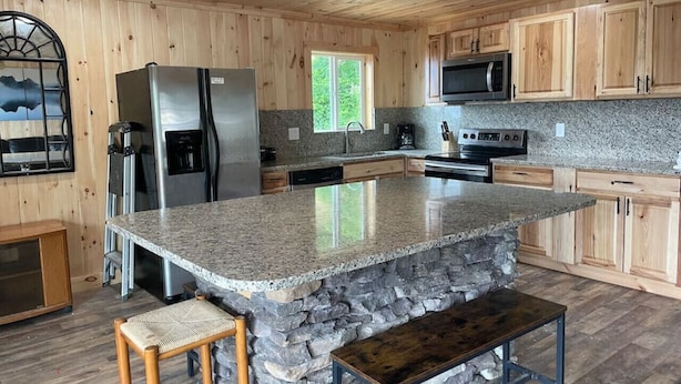 A kitchen with a granite island, wooden cabinets, stainless steel appliances, and a stone countertop. - Crestview-Spectacular 3 bed 3 bath 5 min to slopes (Banner Elk)