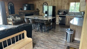 A cozy cabin interior with a stone fireplace, a dining area with a bar, a kitchen with modern appliances, and a comfortable seating area. - Crestview-Spectacular 3 bed 3 bath 5 min to slopes (Banner Elk)