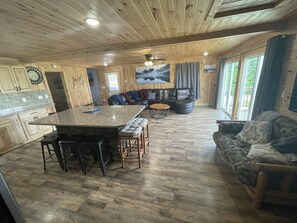 Cozy cabin with a large kitchen, seating area, and dining space, offering a view of the outdoors.