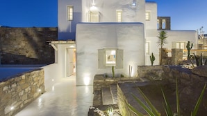 A modern white building with a stone facade, a pool, and a cactus garden.