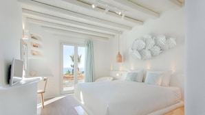 A modern bedroom with a large bed, a TV, and a view of the outdoors.