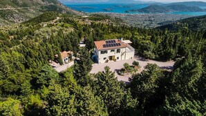 Ein Haus mit Solardach, umgeben von dichtem Wald und Blick auf einen See und Berge.