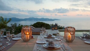An outdoor dining area with a table set for two, overlooking a body of water and distant mountains. - Villa Kothreas - Four Bedroom Villa, Sleeps 8 (Kothreas)