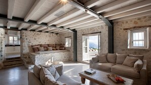 A spacious living area with a stone wall, a sofa, a coffee table, and a view of the outdoors. - Villa Kothreas - Four Bedroom Villa, Sleeps 8 (Kothreas)