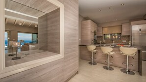 Eine moderne Küche mit Kochinsel, Barhocker und einem großen Kühlschrank.