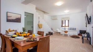 Un espacio de estar moderno con comedor, sofá y televisor.