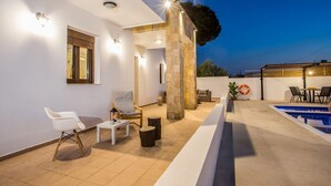 Un espacio exterior moderno con piscina, asientos y un pilar de piedra.