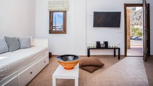 Una habitación moderna con cama, una mesa con un cuenco decorativo, televisor y ventana con vistas al exterior.