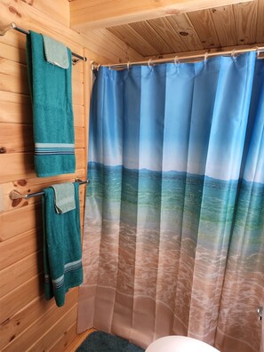 Bañera con ducha, toallas, jabón, shampoo