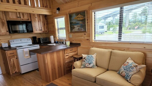 Una cocina acogedora de estilo rústico con armarios de madera, estufa, microondas y una zona de comedor.