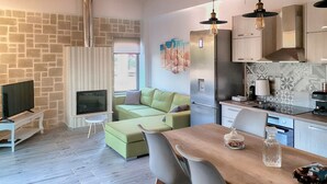 Eine moderne Küche mit integriertem Herd, einem Essbereich mit Holztisch und einer Sitzecke mit einem grünen Sofa.