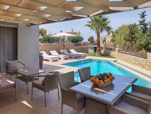 A poolside area with wicker furniture, a table with a fruit bowl, and a view of the pool and surrounding landscape. - Villa Kissamos - Two Bedroom Villa, Sleeps 5 (Nopigia)