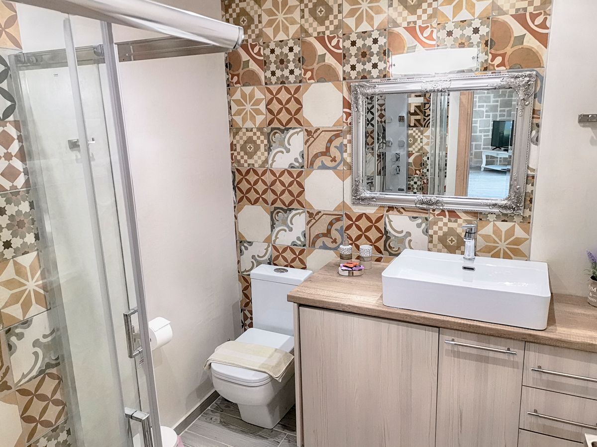 Een badkamer met douche, toilet en wastafel.