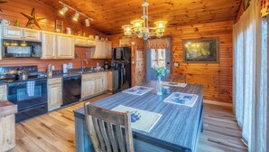 Interior de una cabaña de madera con cocina, comedor y un gran ventanal.
