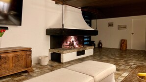 A cozy living room with a fireplace, a wooden cabinet, and a cushioned bench. - Spacious family apartment with a sauna, fireplace, garden, and terrace near Brauneck (Lenggries)