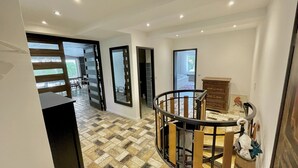 A modern interior with a spiral staircase, a dining area, and a view of a balcony. - Spacious family apartment with a sauna, fireplace, garden, and terrace near Brauneck (Lenggries)