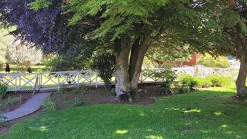 Un jardín con terraza de madera, un camino y una valla blanca.