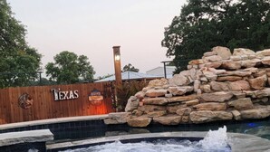 A hot tub area with a wooden fence and a sign that reads "TEXAS HOME". - Safari Cabana at Tipsy Toad Retreat (Boyd)