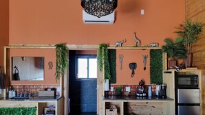 A compact room with a kitchenette, a bed, and a bathroom. - Safari Cabana at Tipsy Toad Retreat (Boyd)